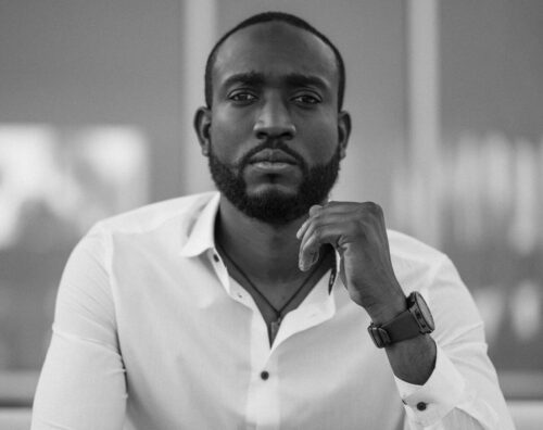 Black and white portrait of a stylish man in a white shirt indoors.