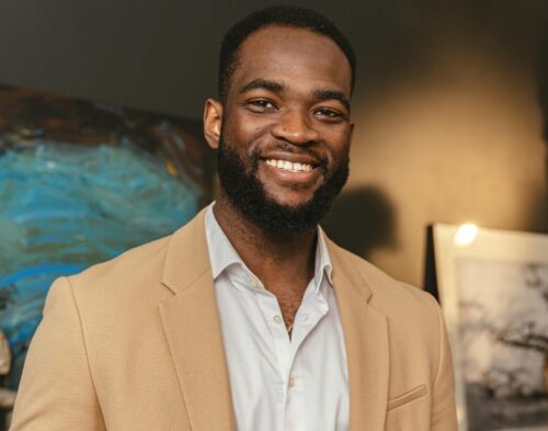 Smiling black businessman holding documents in a modern office setting.